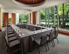Meeting room with U-shaped conference setup, large windows, and garden views at Hilton Boston Logan Airport.