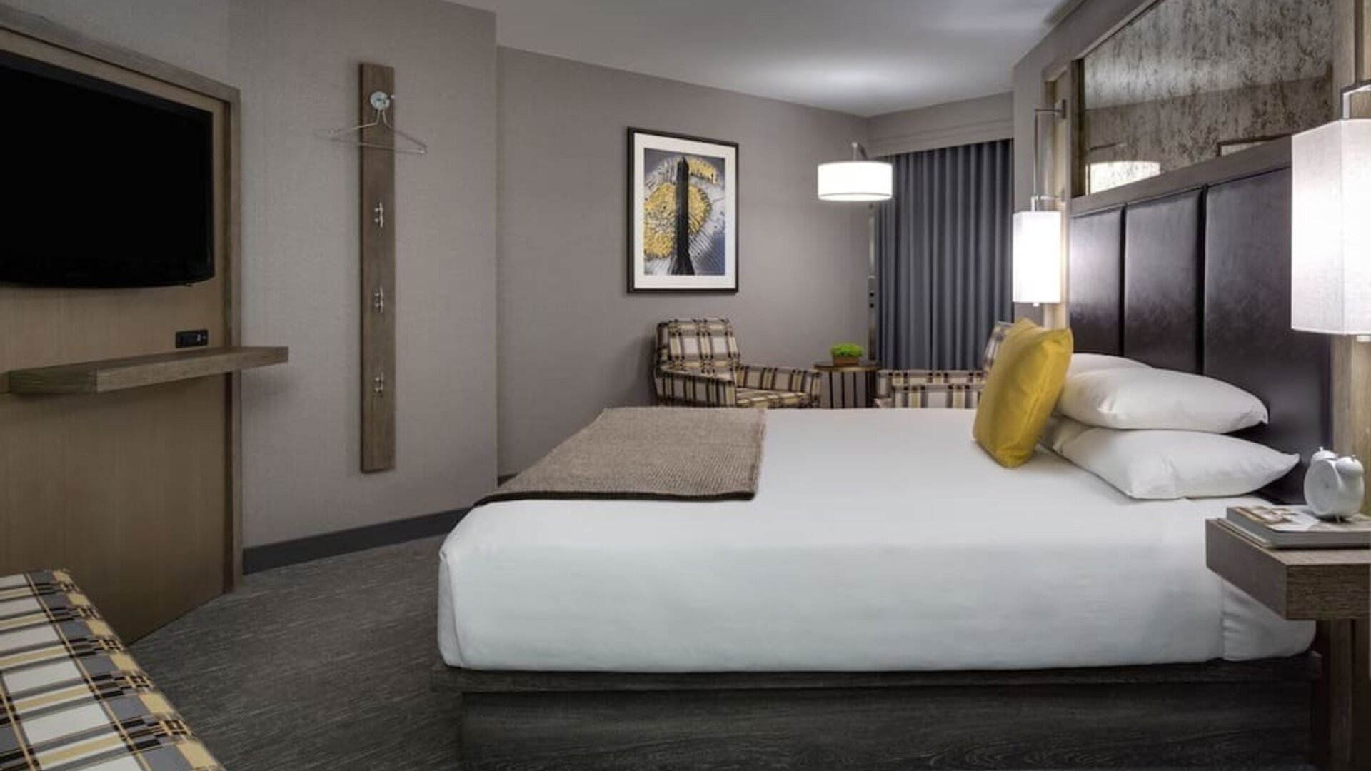 Comfortable king guest room with lounge chairs, modern décor, and warm lighting at Hyatt Regency Boston.