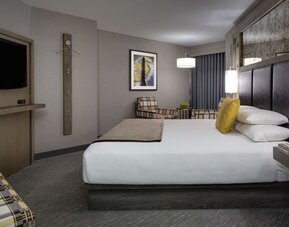 Comfortable king guest room with lounge chairs, modern décor, and warm lighting at Hyatt Regency Boston.