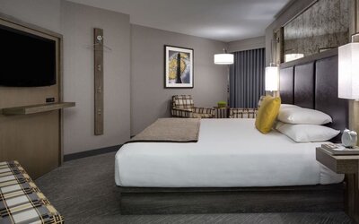 Comfortable king guest room with lounge chairs, modern décor, and warm lighting at Hyatt Regency Boston.