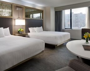 Bright double queen guest room with city views, modern décor, and round table seating at Hyatt Regency Boston.