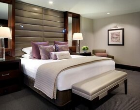 Luxury guest room with king bed, padded headboard, upholstered bench, and elegant neutral décor at Hyatt Regency Boston.