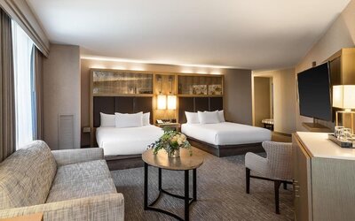 Spacious suite-style guest room with two queen beds, seating area, and modern furnishings at Hyatt Regency Boston.