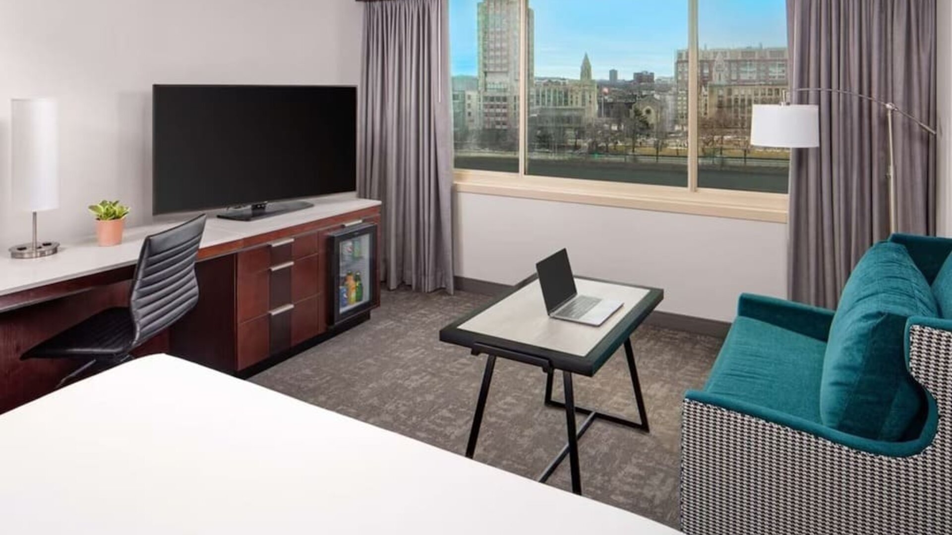 Modern guest room with city and river views, workspace, lounge seating, and large flat-screen TV at Hyatt Regency Boston/Cambridge.