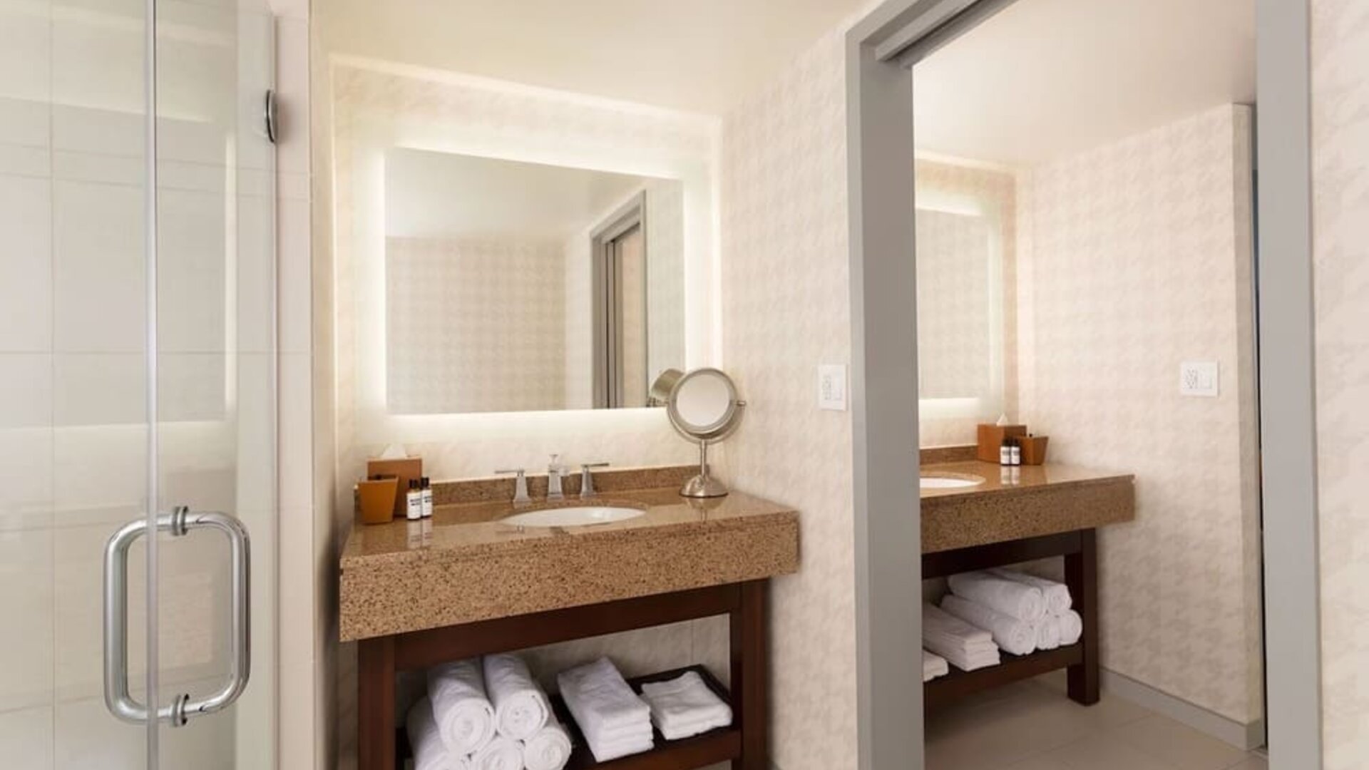 Contemporary bathroom vanity area with illuminated mirror, granite countertop, and glass walk-in shower at Hyatt Regency Boston/Cambridge.
