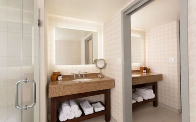 Contemporary bathroom vanity area with illuminated mirror, granite countertop, and glass walk-in shower at Hyatt Regency Boston/Cambridge.