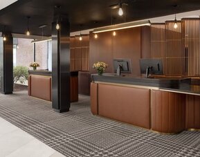 Modern hotel reception desk area with warm wood finishes and contemporary lighting at Hyatt Regency Boston/Cambridge.