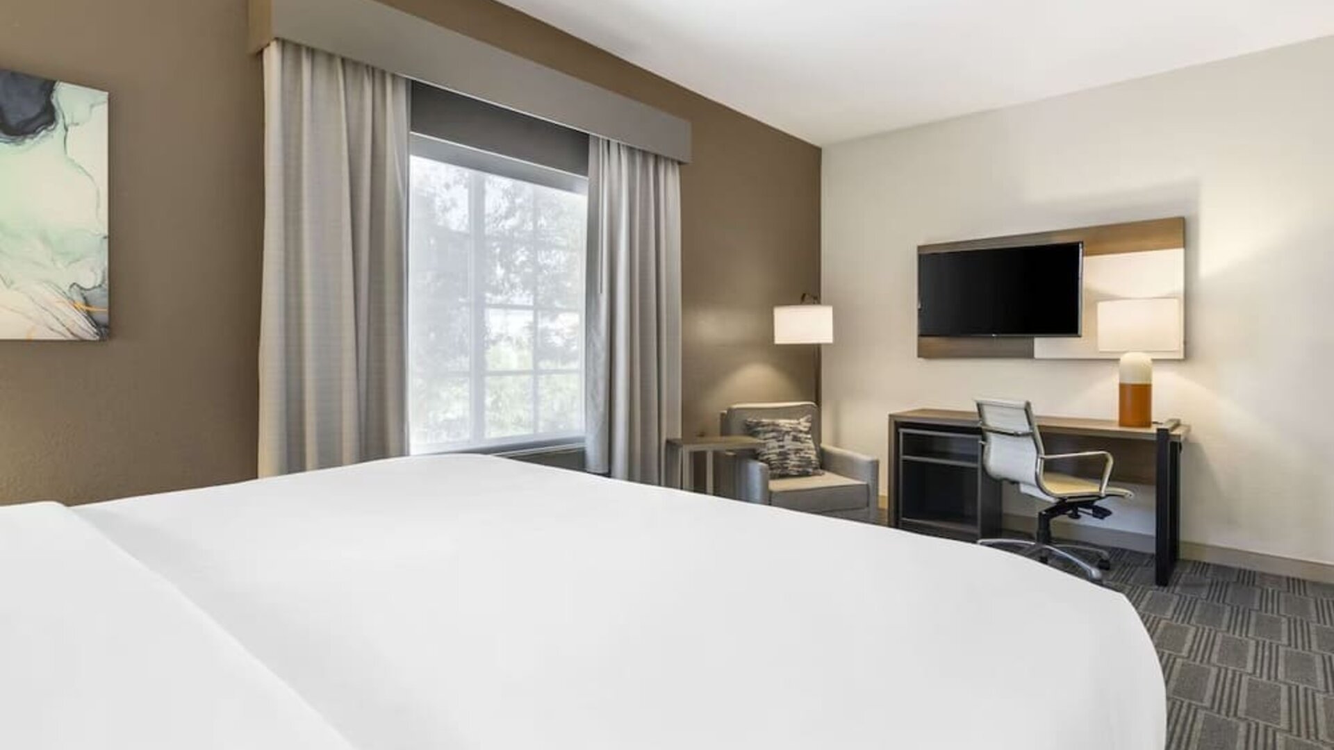Comfortable guest room with workspace, lounge chair, and large window for natural light at Comfort Inn & Suites Port Charlotte-Punta Gorda.