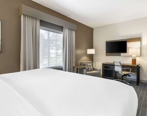 Comfortable guest room with workspace, lounge chair, and large window for natural light at Comfort Inn & Suites Port Charlotte-Punta Gorda.
