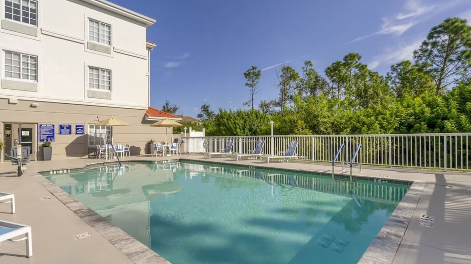Outdoor swimming pool with surrounding sun loungers and peaceful greenery at Comfort Inn & Suites Port Charlotte-Punta Gorda.
