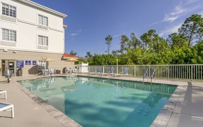 Outdoor swimming pool with surrounding sun loungers and peaceful greenery at Comfort Inn & Suites Port Charlotte-Punta Gorda.