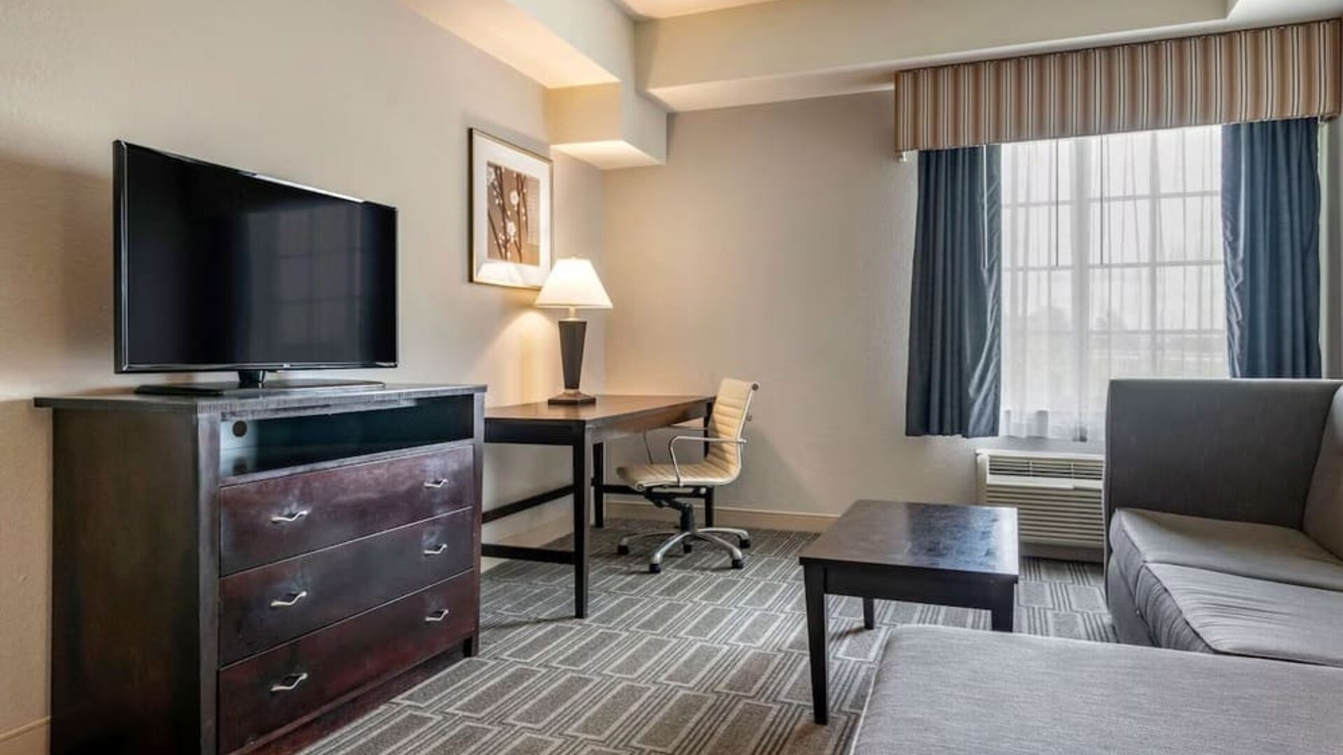Studio-style suite with sofa seating, workspace, and flat-screen television at Comfort Inn & Suites Port Charlotte-Punta Gorda.