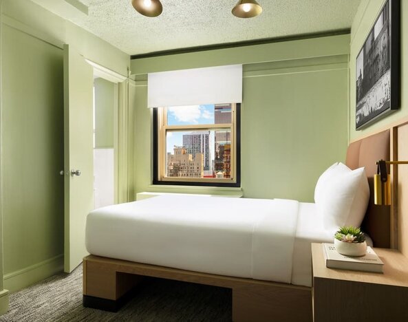 Cozy guest room with natural light, city views, and minimalist modern furnishings at Row NYC.
