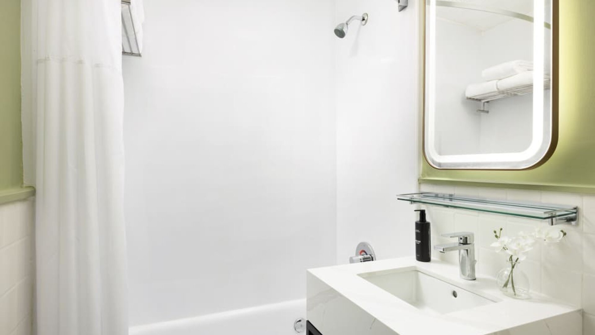 Bright guest bathroom with clean white finishes, modern vanity, and walk-in shower at Row NYC.