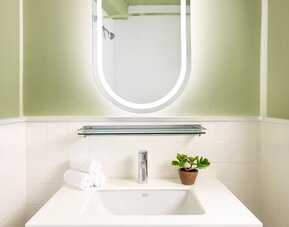 Modern bathroom vanity with illuminated mirror, contemporary sink, and minimalist styling at Row NYC.