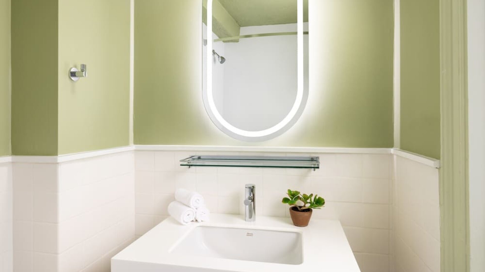 Compact modern bathroom with illuminated mirror, sleek vanity, and contemporary finishes at Row NYC.