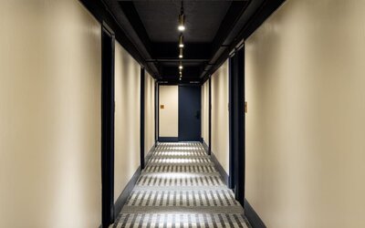 Stylish hotel hallway with patterned carpeting, ambient lighting, and modern guest room entrances at Row NYC.