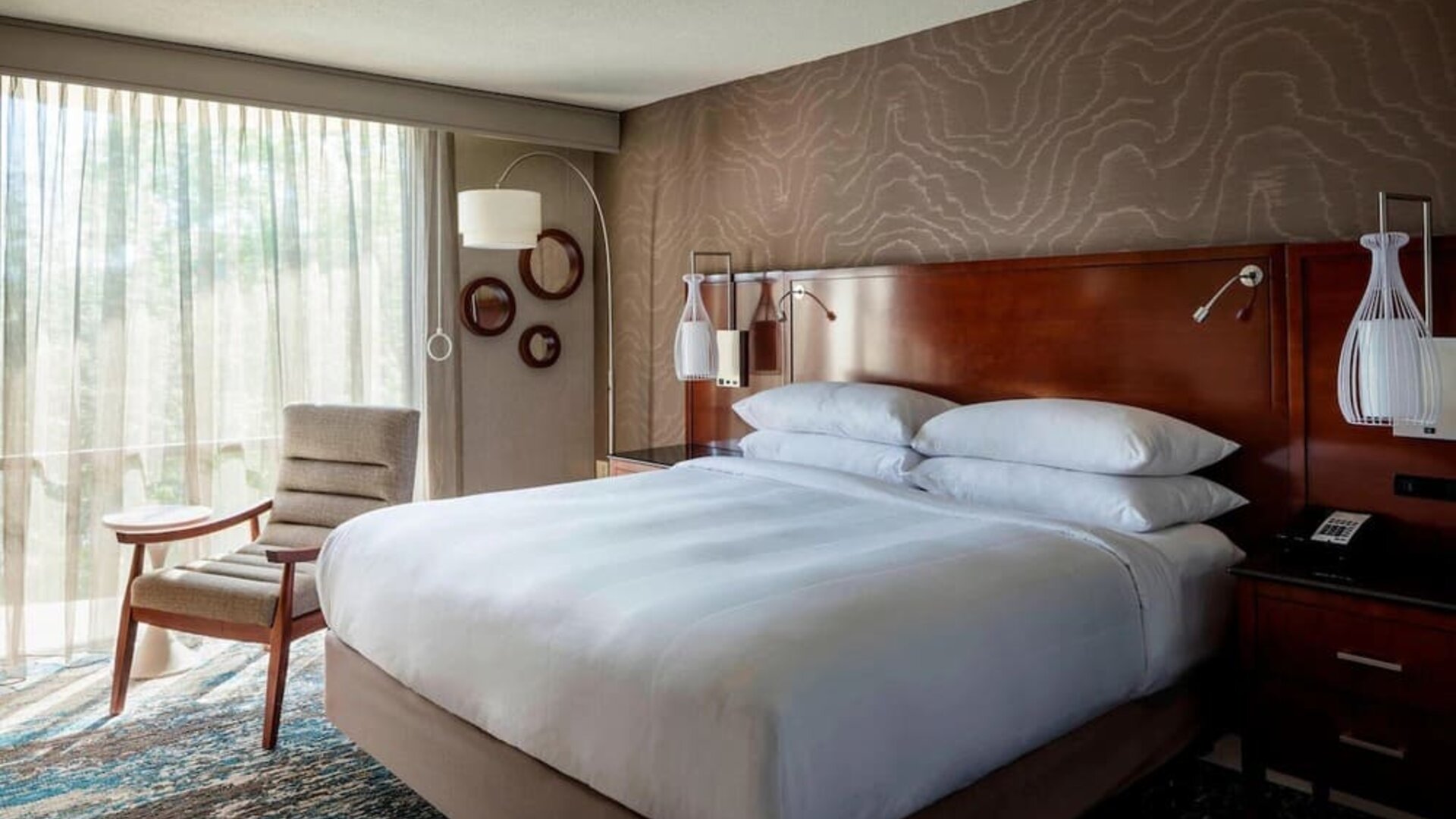 Spacious king guest room with plush bedding, floor-to-ceiling windows, and sophisticated décor at Boston Marriott Newton.