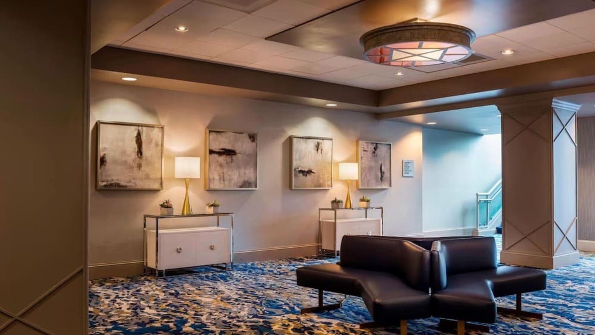 Sophisticated hotel lobby with patterned carpeting, modern seating, and warm ambient lighting at Boston Marriott Newton.