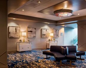 Sophisticated hotel lobby with patterned carpeting, modern seating, and warm ambient lighting at Boston Marriott Newton.