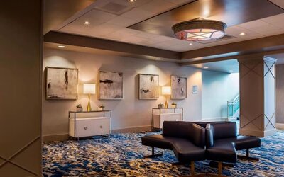 Sophisticated hotel lobby with patterned carpeting, modern seating, and warm ambient lighting at Boston Marriott Newton.