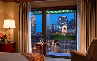 Guest room with scenic balcony and panoramic Boston skyline views at The Bostonian Boston, A Millennium Hotel.