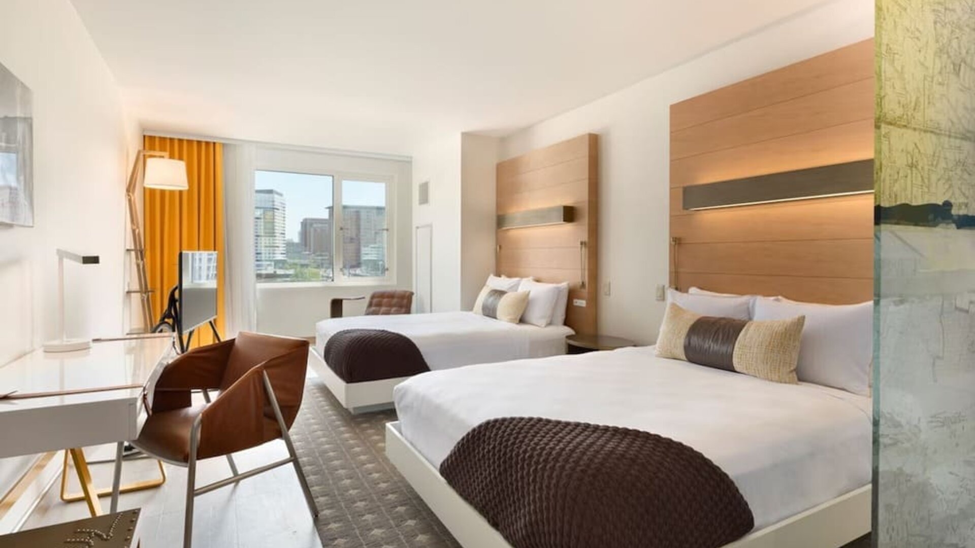 Bright double guest room with two beds, modern furnishings, and large windows offering city views at The Envoy Hotel, Autograph Collection.