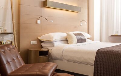 Contemporary king guest room featuring warm wood accents, plush bedding, and stylish modern furnishings at The Envoy Hotel, Autograph Collection.