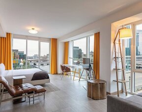 Spacious modern suite with open-plan design, city views, contemporary décor, and comfortable lounge seating at The Envoy Hotel, Autograph Collection.