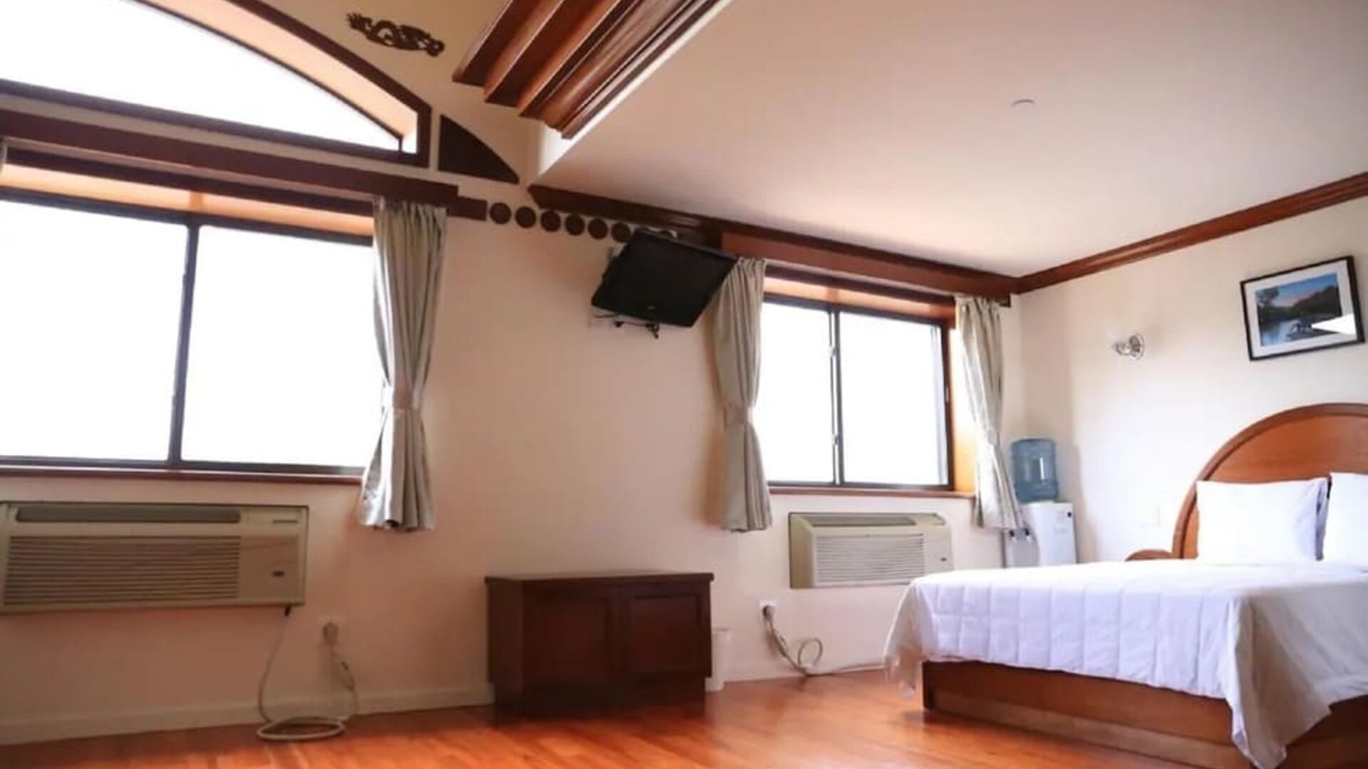 Spacious guest room with hardwood flooring, large windows, and natural light at Phoenix Hotel Brooklyn Sunset Park.