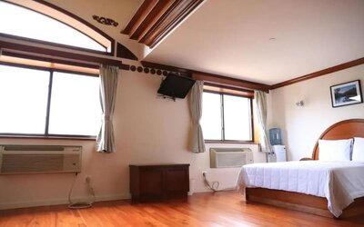 Spacious guest room with hardwood flooring, large windows, and natural light at Phoenix Hotel Brooklyn Sunset Park.