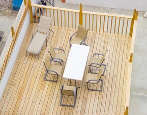 Outdoor seating deck with lounge chairs and dining table available for guests at Phoenix Hotel Brooklyn Sunset Park.