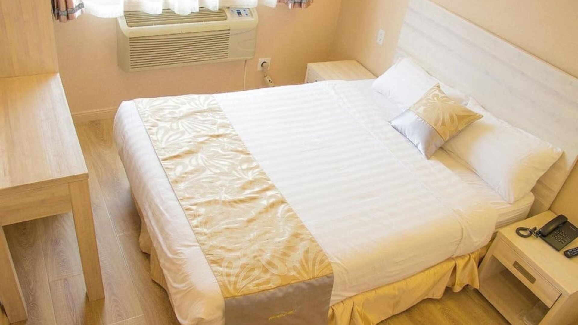 Cozy king bedroom with light wood furnishings and minimalist décor at Phoenix Hotel Brooklyn Sunset Park.