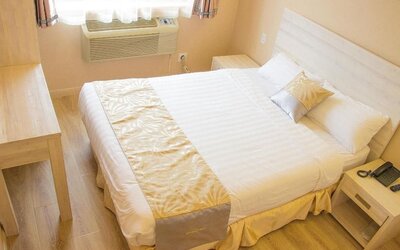 Cozy king bedroom with light wood furnishings and minimalist décor at Phoenix Hotel Brooklyn Sunset Park.