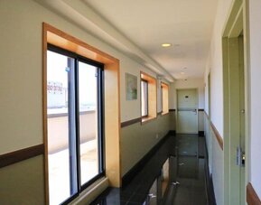 Clean and modern hotel corridor with large windows allowing natural daylight into the passageway at Phoenix Hotel Brooklyn Sunset Park.