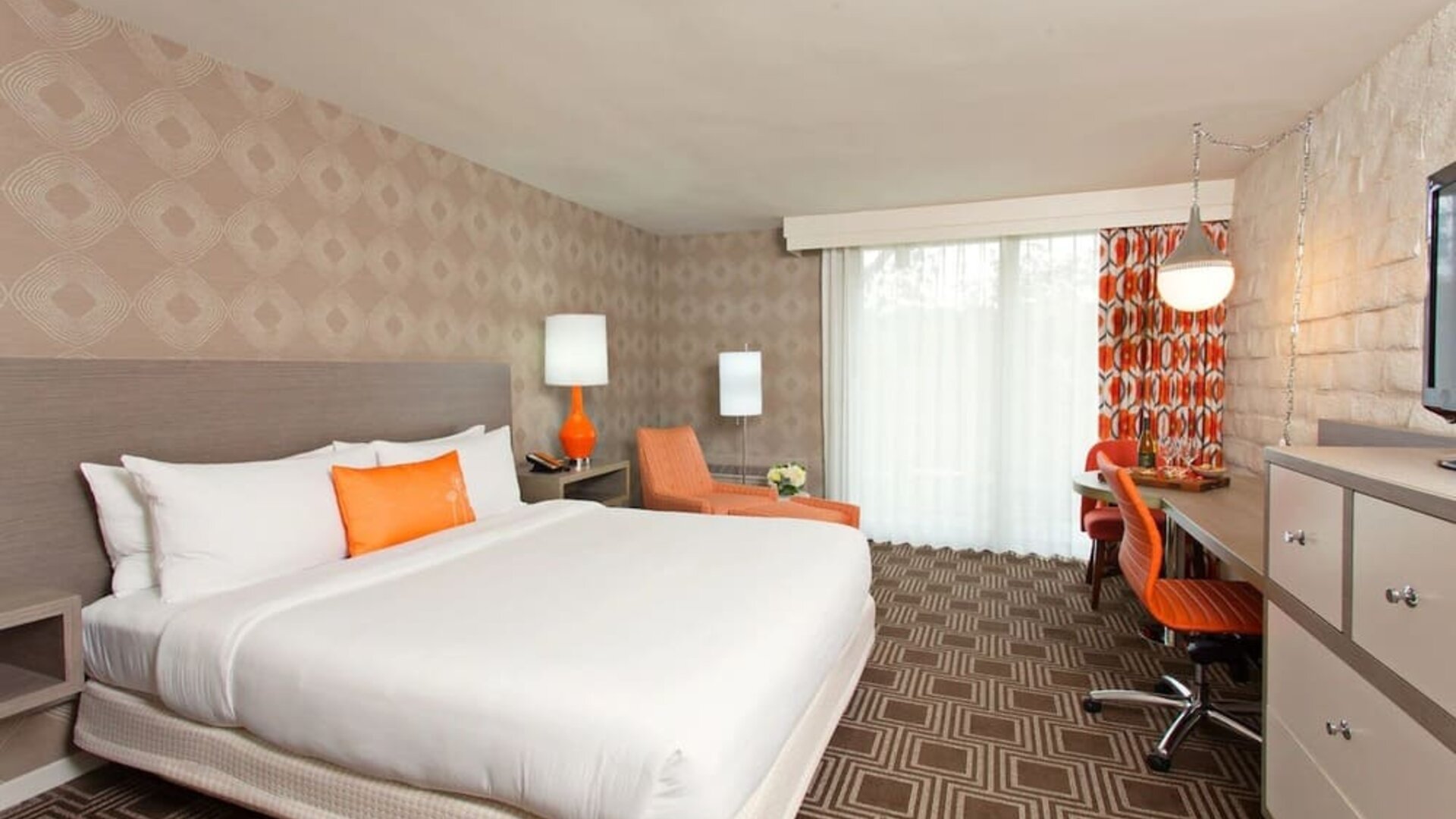 Spacious king guest room with private balcony access, work desk, and vibrant accent furnishings at The Garland.