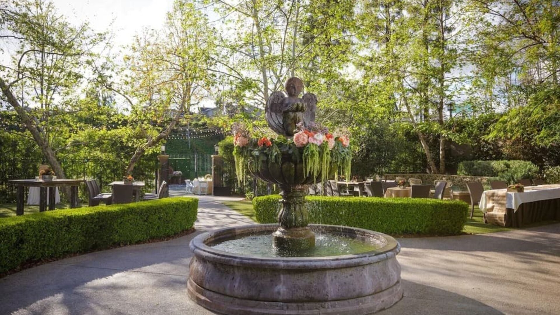 Beautiful landscaped garden courtyard with a decorative fountain surrounded by lush greenery and outdoor seating at The Garland.