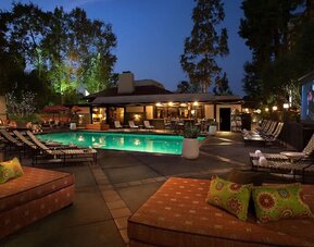 Resort-style outdoor swimming pool area with lounge chairs, evening lighting, and open-air relaxation spaces at The Garland.