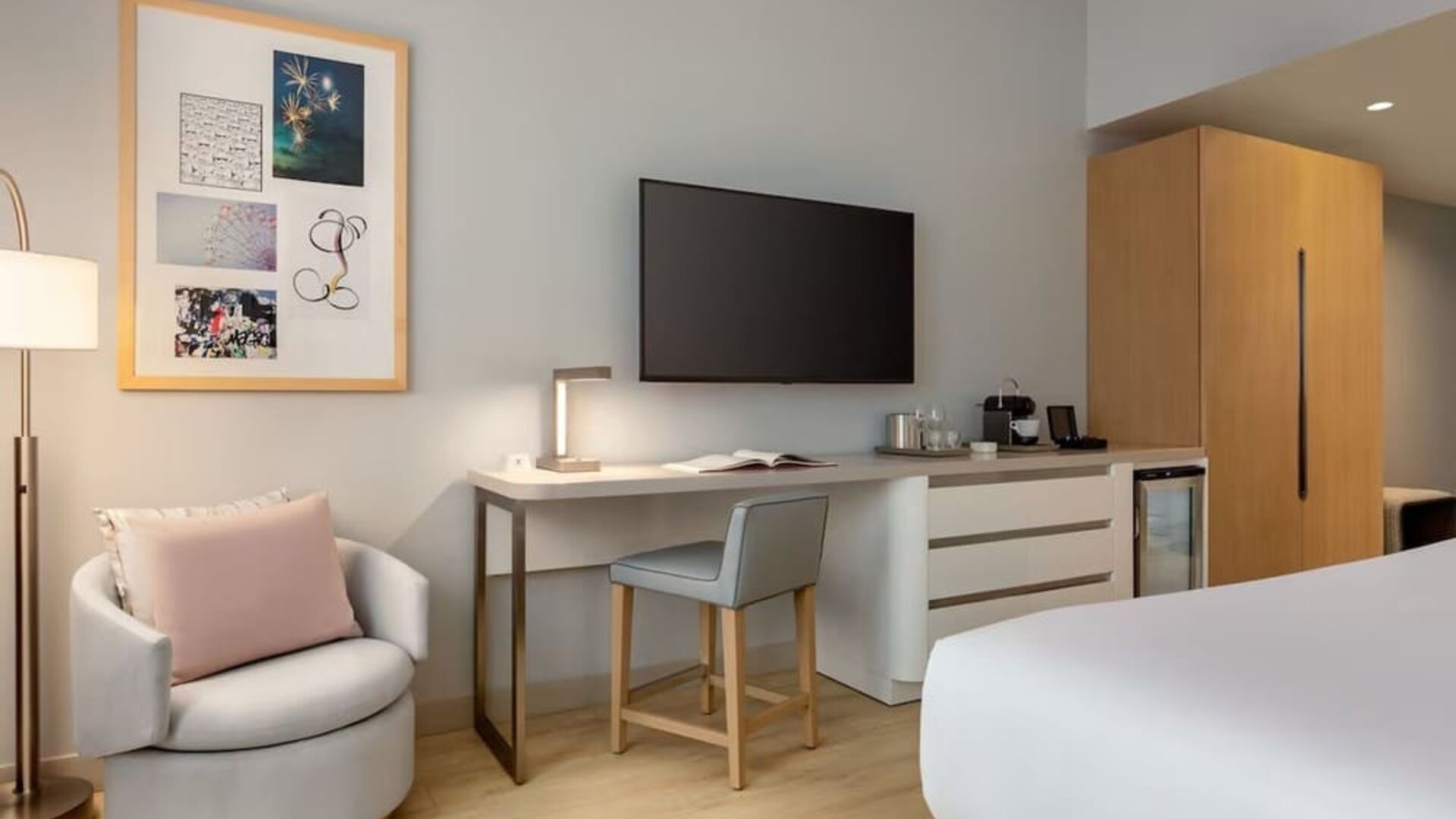 In-room workspace and entertainment area featuring a large flat-screen television, desk, seating, and convenient storage amenities.