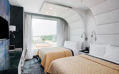 Double-queen guest room featuring two beds, large windows, reading lights, modern furnishings, and a comfortable layout suitable for families or groups.