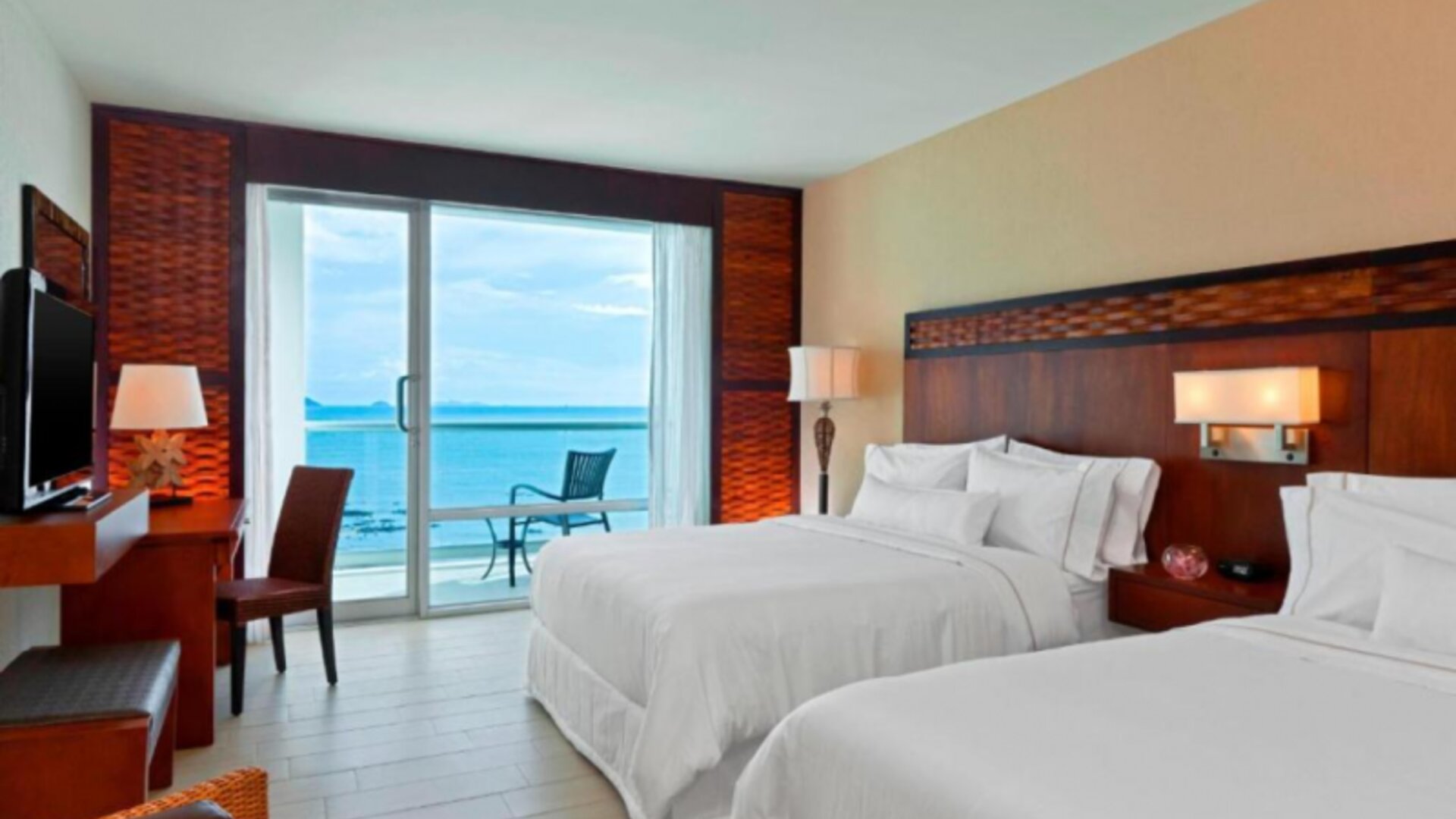 Deluxe Double Room with Ocean View, featuring two beds, a private bathroom with amenities, a safe, a desk, a telephone, ironing facilities, a tea/coffee maker, a hairdryer, a television, cable channels, and an alarm clock.
